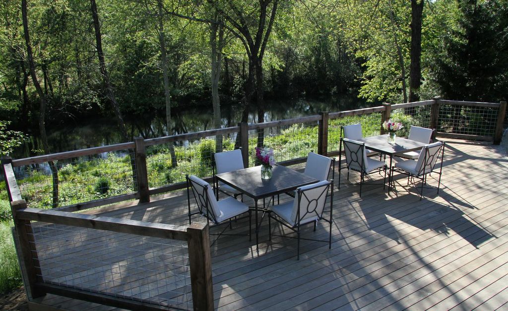 Outdoor deck at 32 Winds Winery nestled in the trees and overlooking Dry Creek with tables and chairs ready for guests.
